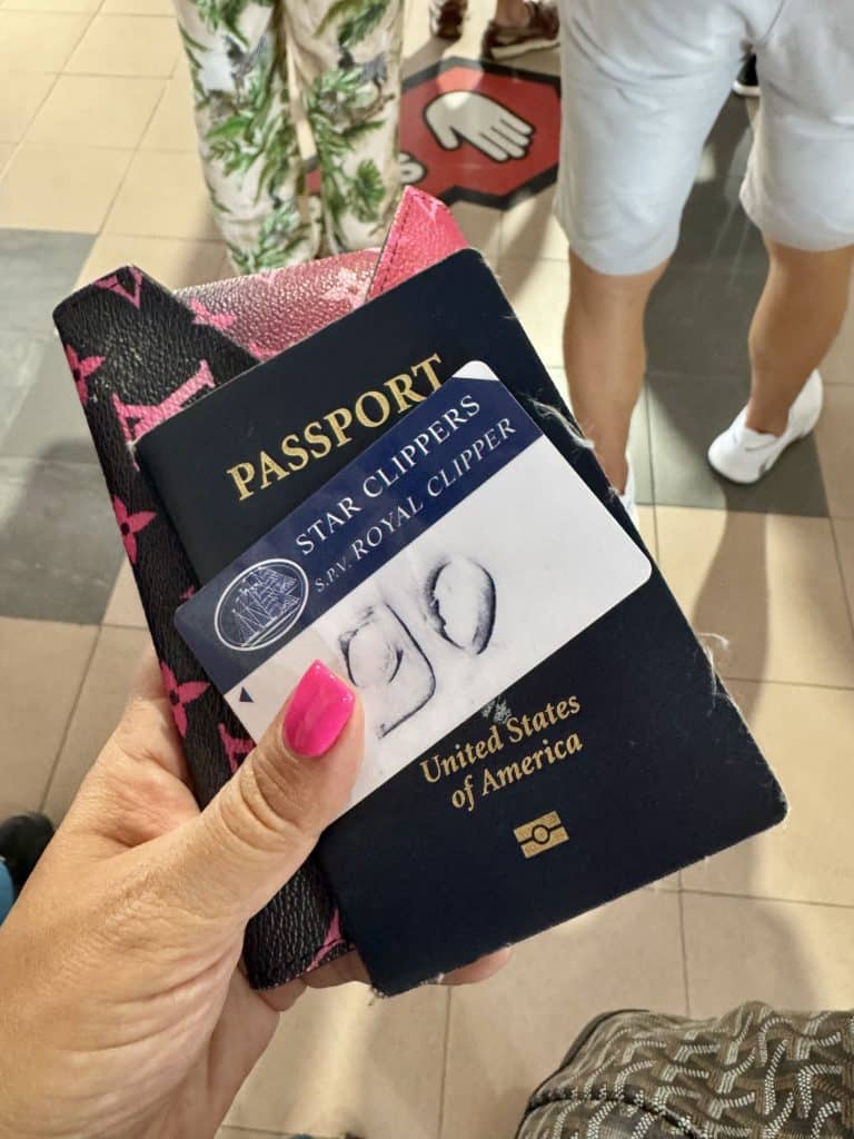 Kate's hand holding her passport and a Star Clippers boarding card.