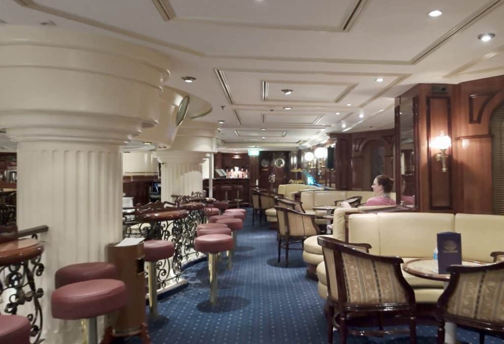 A lounge with lots of seats and booths, one dark-haired woman sitting in one booth.