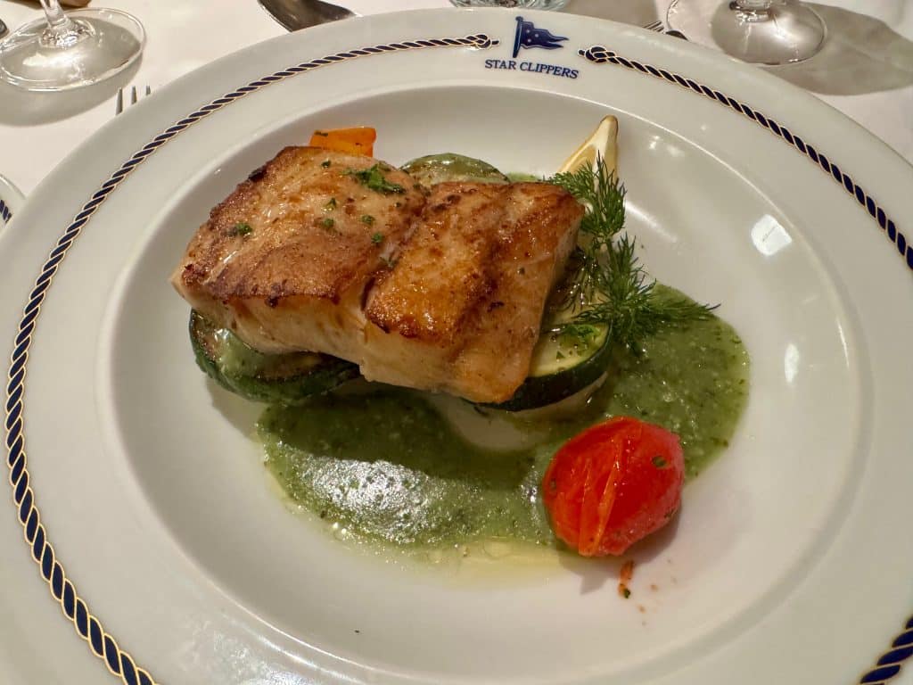 A red snapper filet sitting on zucchini and mashed potatoes.