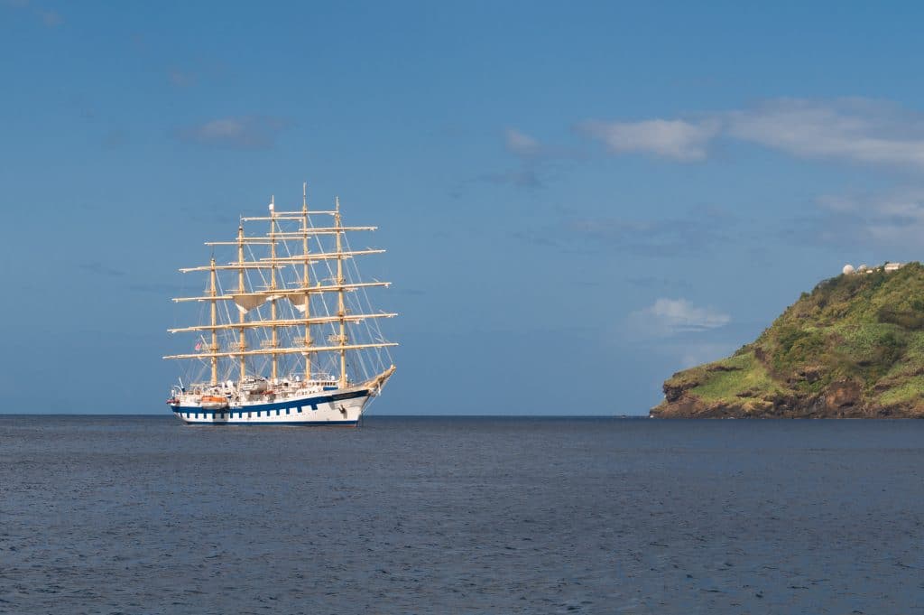 The five-masted Royal Clipper ship, anchored in a small bay.
