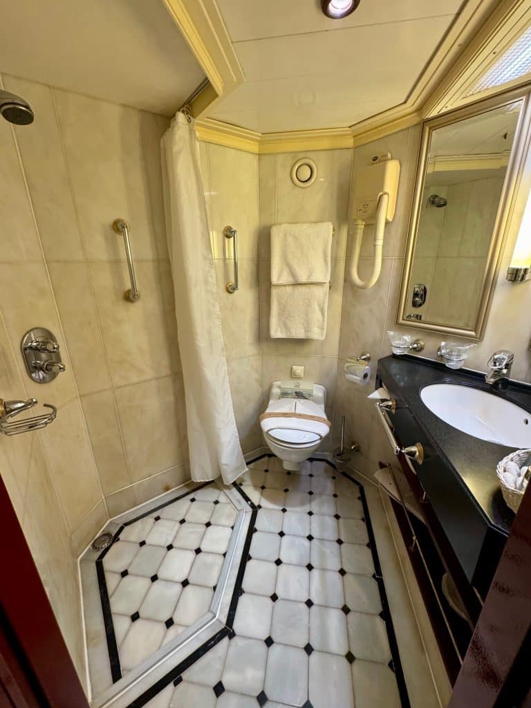 A small cabin bathroom with a tiny shower area, toilet, and sink.