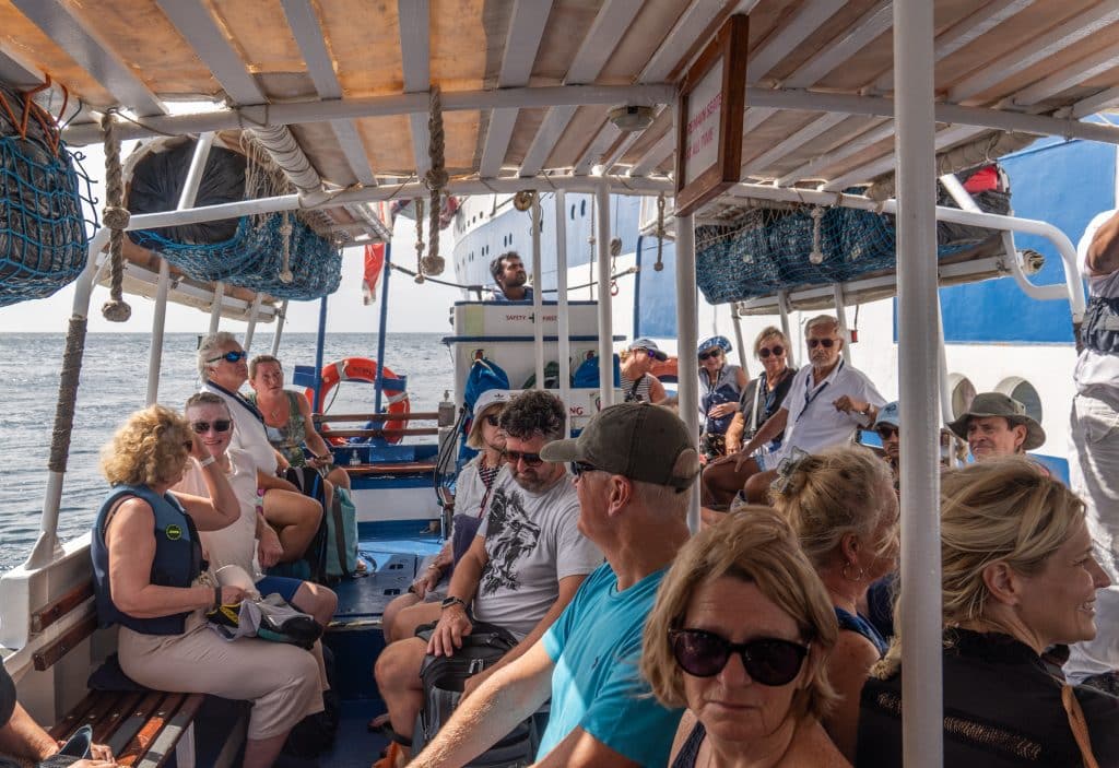 A crowd of people sitting on a small covered tender boat.