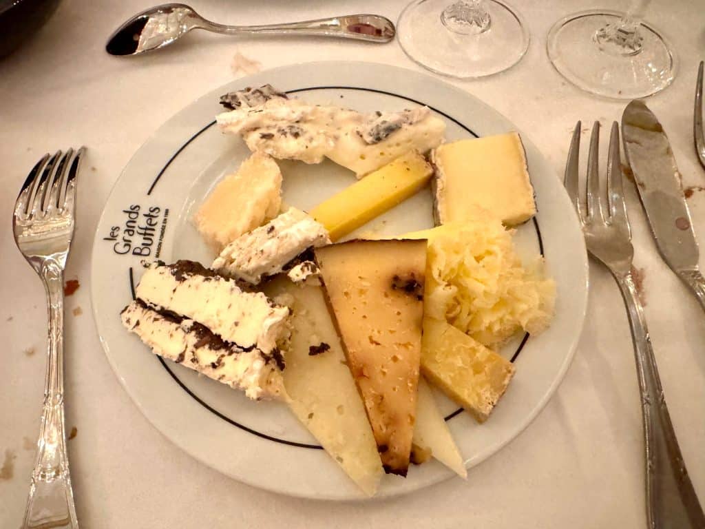 A plate full of several cheeses, some soft, some hard, some full of truffles.