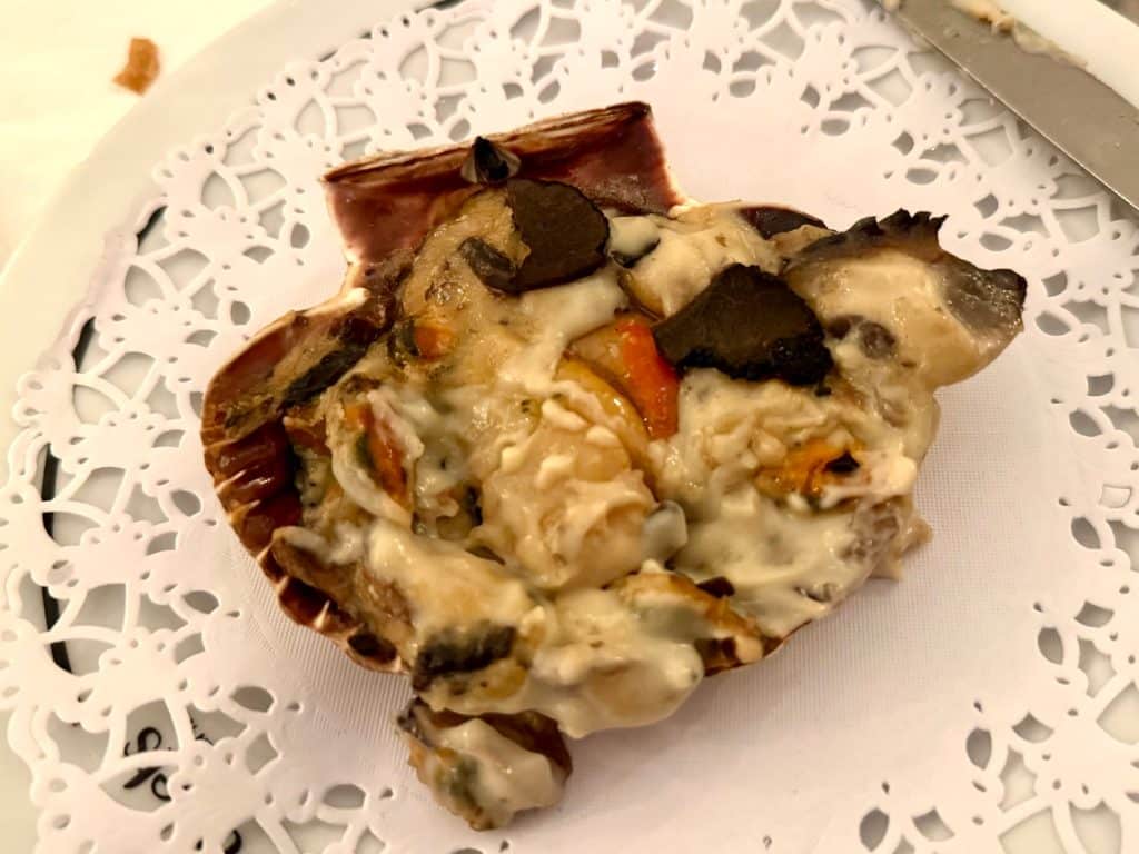 A big scallop shell with Coquilles St. Jacques on the inside, scallops and creamed vegetables.