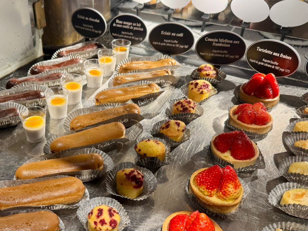 Rows of desserts: eclairs, strawberry tarts, little custards.