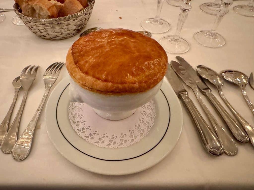 A large soup with a sheet of crust on top of it.