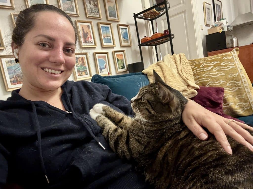 Kate sitting on the couch with Lewis the gray tabby cat in her lap, looking at her, with his paws on her chest.