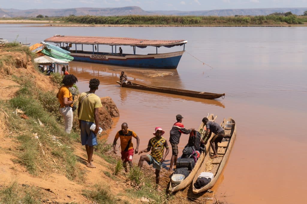 A group of local men preparing wooden canoes to transport locals to a boat.