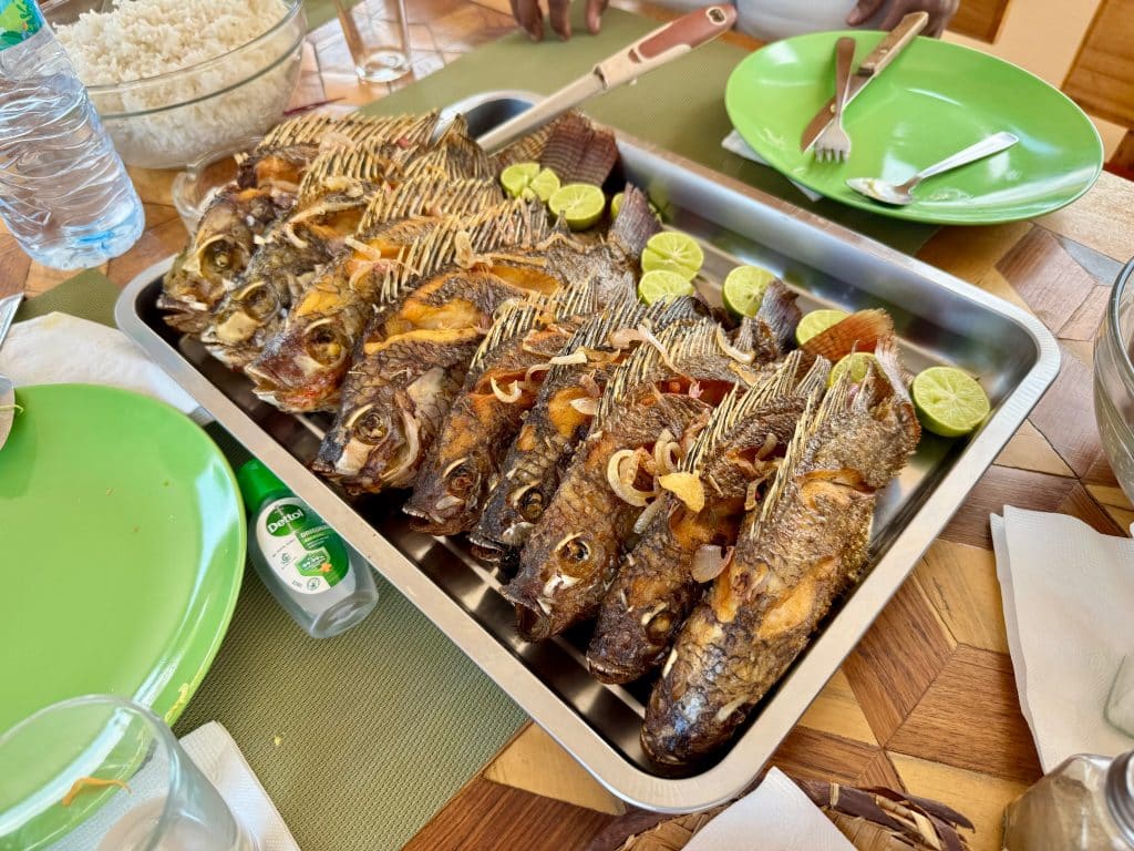 A big pan of small fried fish, serve next to slices of lime.
