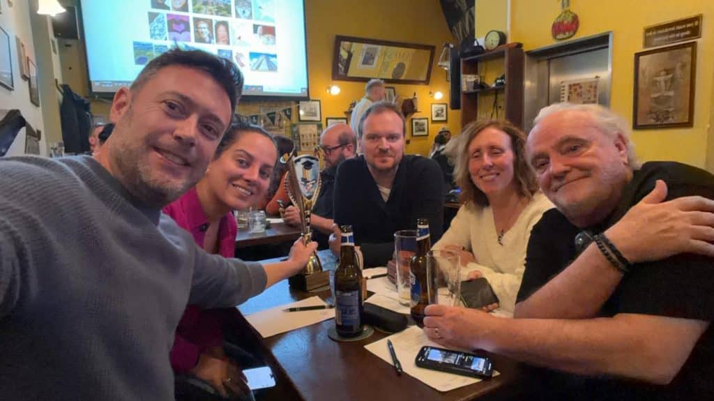 Kate and friends in a bar, posing with their statue after winning trivia.
