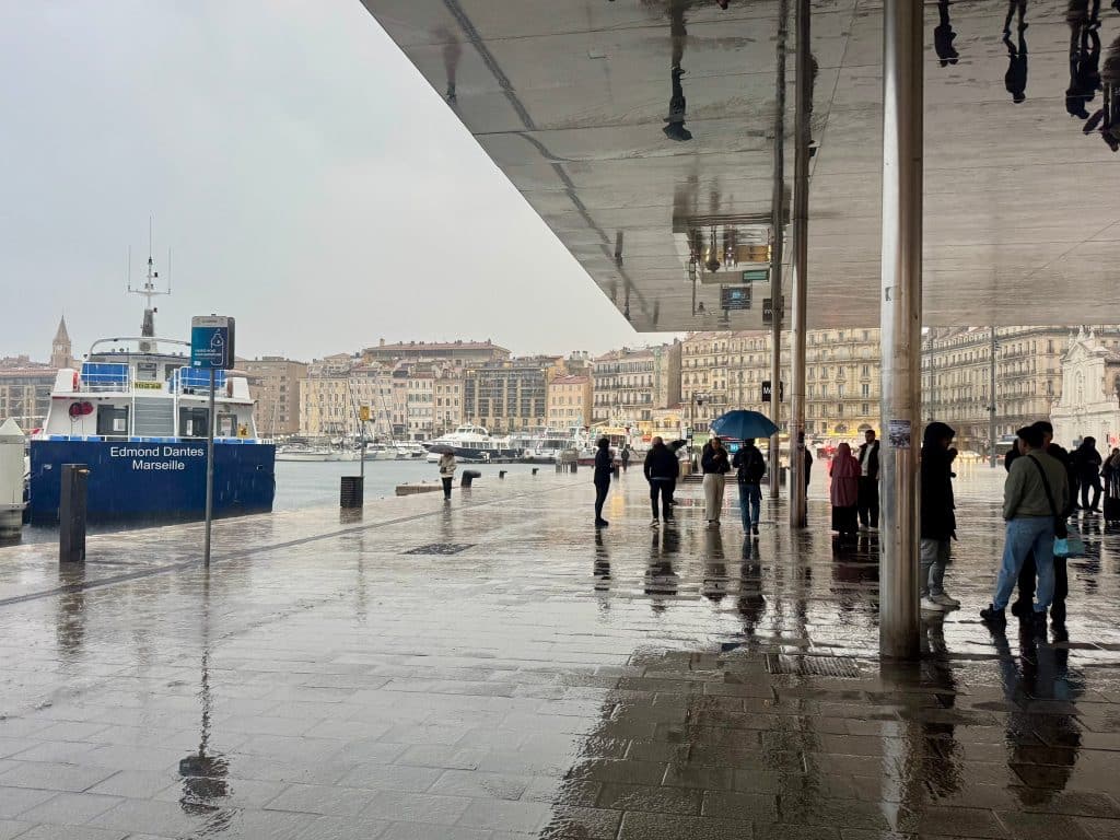 People huddling beneath a platform on a very rainy day at the port in Marseille.