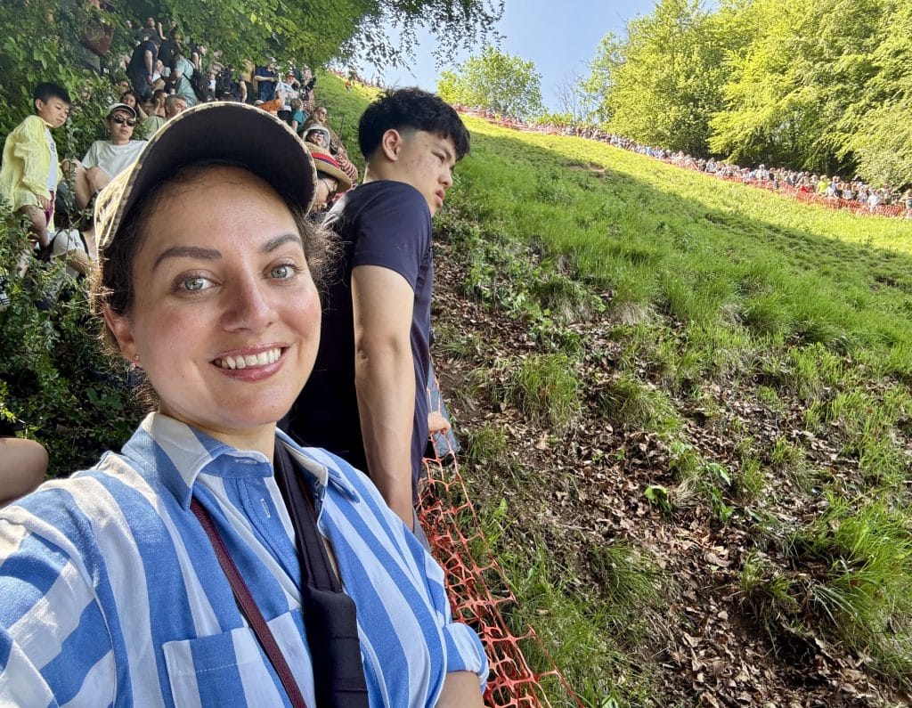 Kate mengambil selfie sambil tersenyum sambil berdiri di samping bukit.