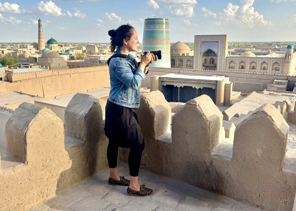 Kate standing above a sand-colored town with turquoise minarets and mosques in the background.