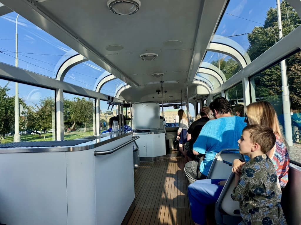 A fancy tram with a bar and white leather seats, and lots of windows for seeing the outside.