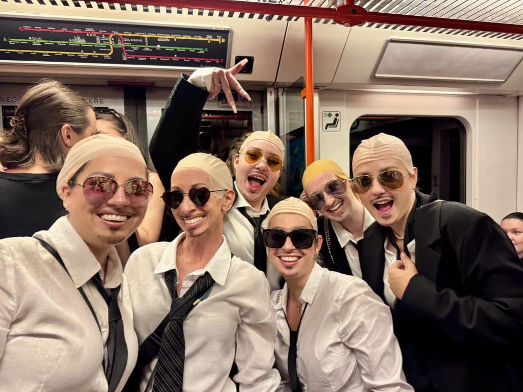Kate, Ashley, and a bunch of people all wearing bald caps and sunglasses while riding the metro in Prague.