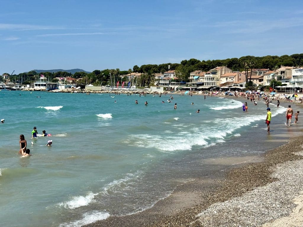 A beach in France with turquoise water, strong waves, and gray pebbles on shore.