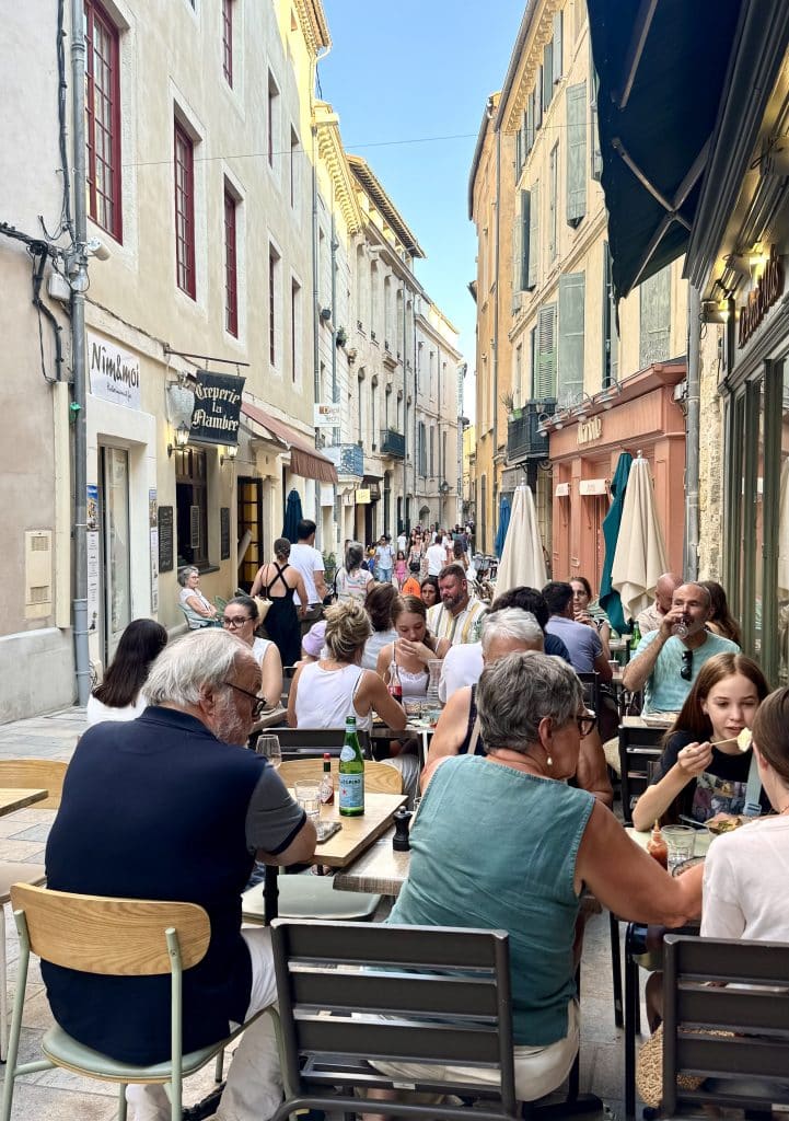 People sitting at outdoor restaurants on the streets of Nimes, France.