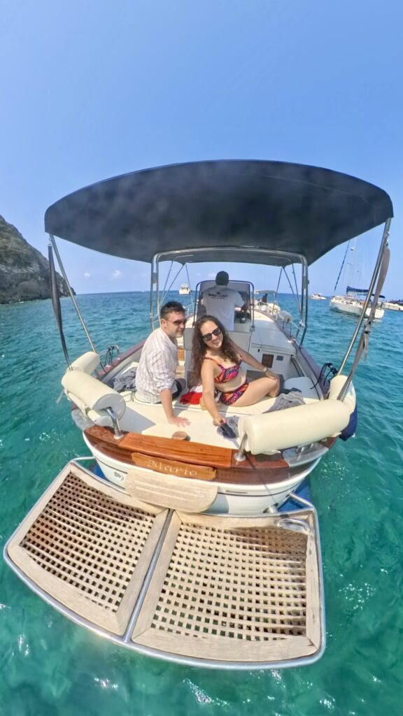 Kate and Charlie sitting on the back of a boat in the turquoise waters surrounding Ischia, Italy