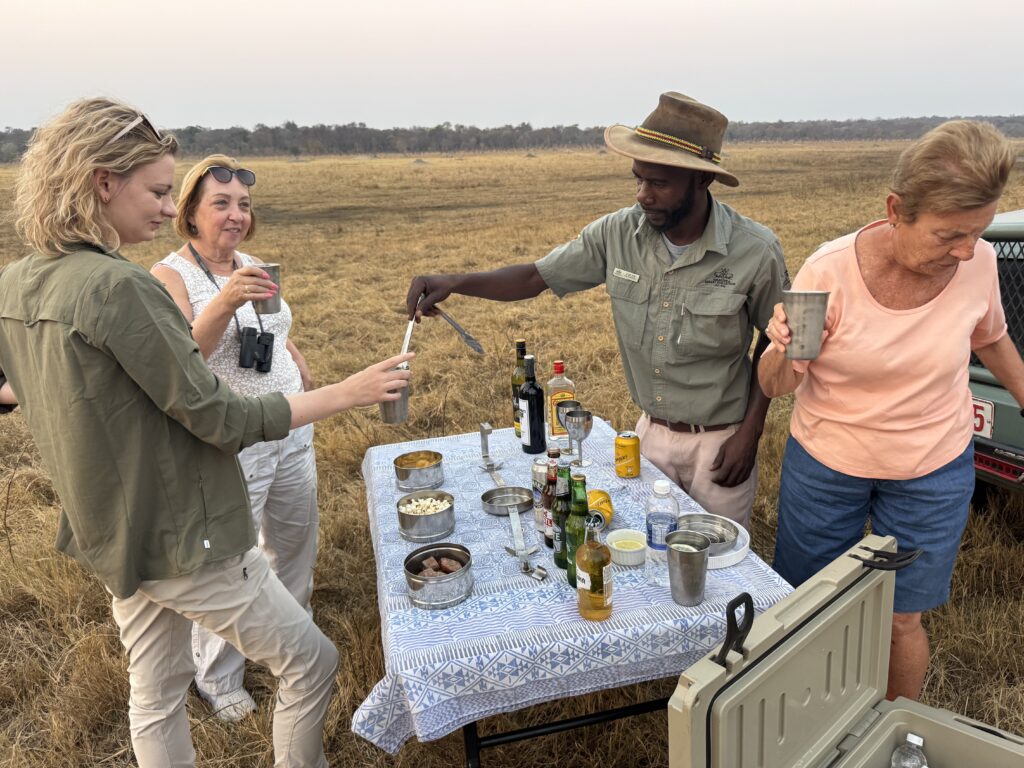 A group of people enjoying cocktails while out in the bush post-safari.